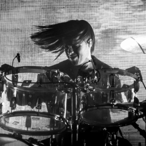 black and white image of jonny playing the drums with his hair sweeping to the side