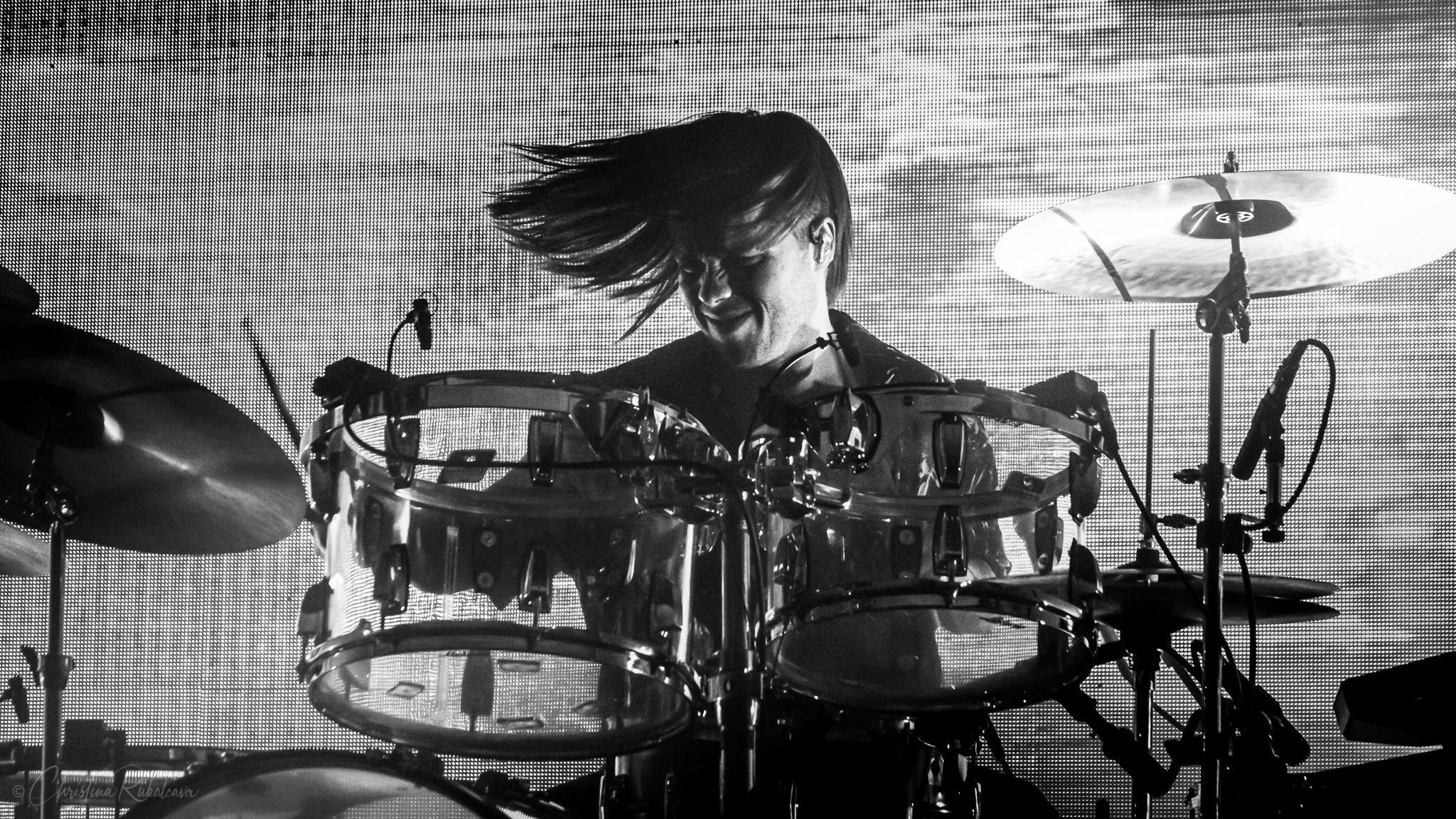 black and white image of jonny playing the drums with his hair sweeping to the side