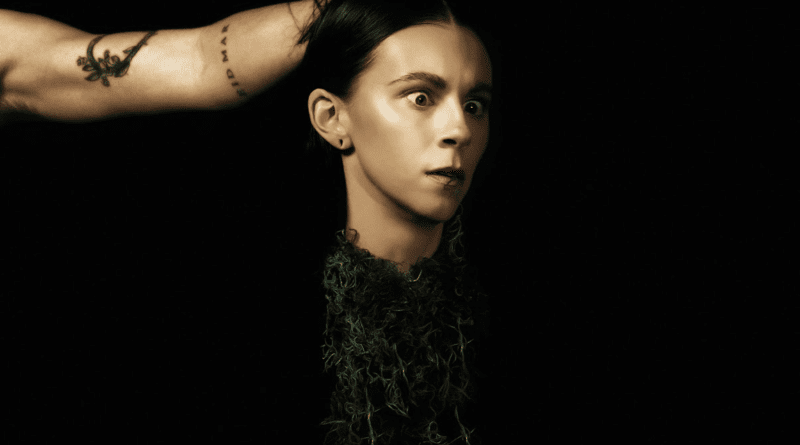 black background and an arm coming in from the left side holding Lynn's severed head by the hair